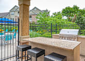 Thumbnail 17 of 50 - A black metal fence surrounds a concrete bar area with two black stools.