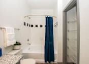 Thumbnail 36 of 50 - A small bathroom with a white tub and a blue shower curtain.
