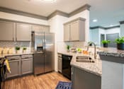 Thumbnail 2 of 50 - A kitchen with a stainless steel refrigerator and a marble countertop.