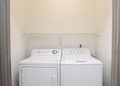 Thumbnail 43 of 50 - Two white front loading washing machines in a small laundry room.