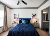 Thumbnail 33 of 50 - A bedroom with a blue bedspread and a ceiling fan.