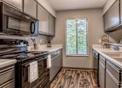Thumbnail 3 of 34 - A kitchen with a stove top oven and a microwave above it.