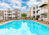 Thumbnail 6 of 18 - A large swimming pool in front of apartment buildings.