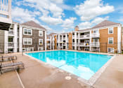 Thumbnail 5 of 18 - A large swimming pool in front of apartment buildings.