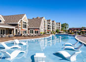 Thumbnail 9 of 53 - a large swimming pool with white chairs in front of apartment buildings  at Waterside Residences on Quivira, Lenexa, Kansas