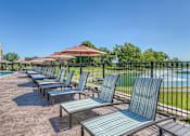 Thumbnail 14 of 53 - a row of lounge chairs and umbrellas next to a swimming pool  at Waterside Residences on Quivira, Lenexa, KS