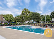 Thumbnail 13 of 28 - A large outdoor swimming pool surrounded by trees and lounge chairs.