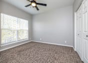 Thumbnail 23 of 28 - A room with a ceiling fan and carpeted floor.