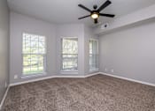 Thumbnail 15 of 28 - A room with a ceiling fan and carpeted floor.