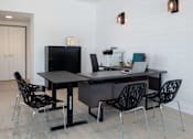 Thumbnail 17 of 18 - A black desk with four chairs and a laptop on it.