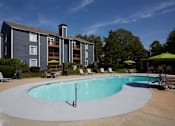Thumbnail 10 of 34 - A swimming pool in front of a grey apartment building.