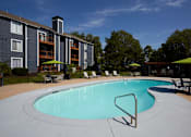 Thumbnail 11 of 34 - A swimming pool in front of a building with a green lawn.