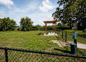 Thumbnail 23 of 34 - A park with a swing set and a fence.