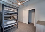 Thumbnail 12 of 15 - a bedroom with bunk beds and a closet and a ceiling fan