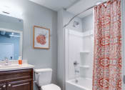 Thumbnail 8 of 15 - a bathroom with a shower curtain and a toilet and a sink