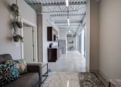 Thumbnail 11 of 15 - a long hallway with a couch and a kitchen in a building