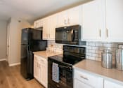 Thumbnail 5 of 25 - A kitchen with black appliances and white cabinets.