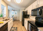 Thumbnail 4 of 25 - A modern kitchen with black appliances and white cabinets.