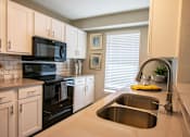 Thumbnail 6 of 25 - A kitchen with a black stove top oven and a black microwave.