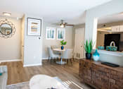 Thumbnail 25 of 25 - A living room with a grey couch, a white coffee table, a wooden cabinet, and a mirror on the wall.
