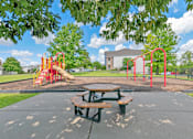 Thumbnail 26 of 50 - A playground with a red swing set and a picnic table.