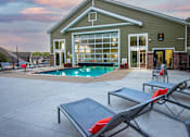 Thumbnail 2 of 25 - A poolside lounge area with sunbeds and a building in the background.