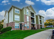 Thumbnail 11 of 25 - A two-story apartment building with a green and beige exterior.