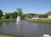 Thumbnail 2 of 23 - a fountain in the middle of a pond with houses in the background