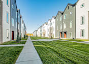Thumbnail 16 of 18 - A row of modern houses with a sidewalk in the foreground.