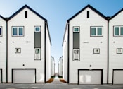 Thumbnail 12 of 18 - A row of white houses with black garage doors.