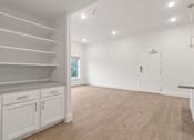 Thumbnail 13 of 15 - A white room with wooden floors and a staircase on the left side.
