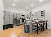Thumbnail 11 of 12 - A kitchen with a table and chairs and a fridge.
