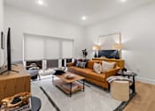 Thumbnail 10 of 12 - A modern living room with a brown sofa and a television.
