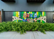 Thumbnail 14 of 15 - A mural of a man with a guitar is painted on a wall.