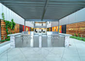 Thumbnail 3 of 12 - A modern outdoor kitchen with two grills and a counter.