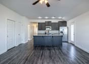 Thumbnail 4 of 15 - A kitchen with a dark wood floor and white walls.