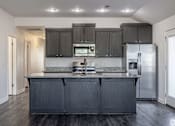 Thumbnail 3 of 15 - A kitchen with black cabinets and a stainless steel refrigerator.