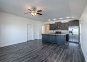 Thumbnail 2 of 15 - A spacious kitchen with dark wood floors and white walls.