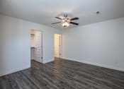 Thumbnail 9 of 15 - A room with a ceiling fan and wooden flooring.