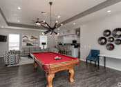 Thumbnail 3 of 23 - A pool table is in the middle of a room with a ceiling fan and a chair.