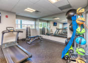 Thumbnail 16 of 34 - a gym with exercise equipment and weights in the corner of a room