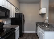 Thumbnail 24 of 37 - a kitchen with black appliances and granite counter tops and white cabinets