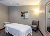 Thumbnail 40 of 59 - A bedroom with a bed, chair, and painting on the wall.
