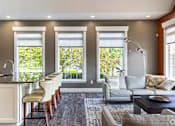 Thumbnail 1 of 44 - A well-lit, modern kitchen with a bar area and a seating area.