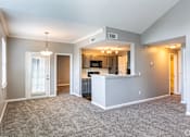 Thumbnail 12 of 44 - A spacious living room with a kitchen area in the background.