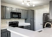 Thumbnail 8 of 44 - A kitchen with black cabinets and a white counter.