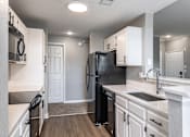 Thumbnail 11 of 44 - A black refrigerator in a kitchen with white cabinets.