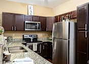 Thumbnail 8 of 14 - A kitchen with a refrigerator, sink, and cabinets.