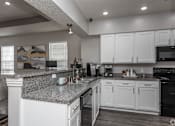 Thumbnail 20 of 23 - A kitchen with white cabinets and a granite countertop.