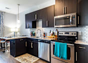 Thumbnail 3 of 53 - a modern kitchen with stainless steel appliances and dark wood cabinets  at Waterside Residences on Quivira, Lenexa
